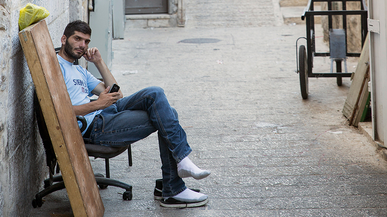 A man holds his phone while sat on a chair.