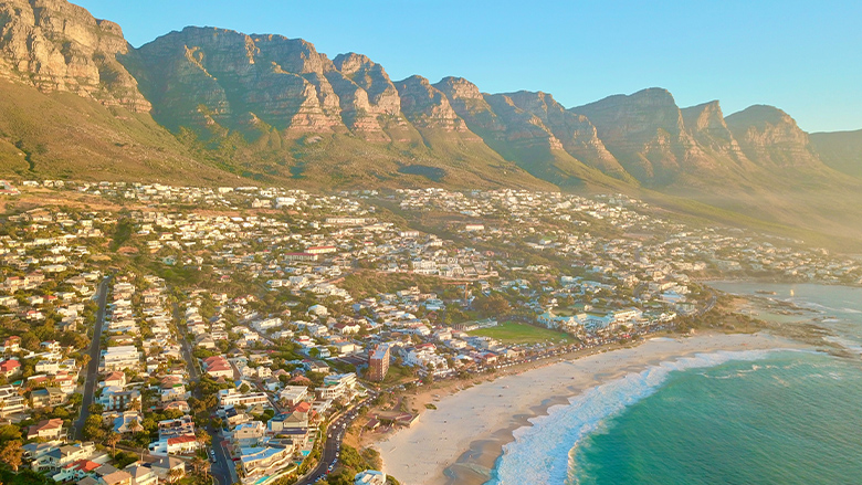 Aerial view of Cape Town, South Africa, showing houses and the shore with a blue ocean.