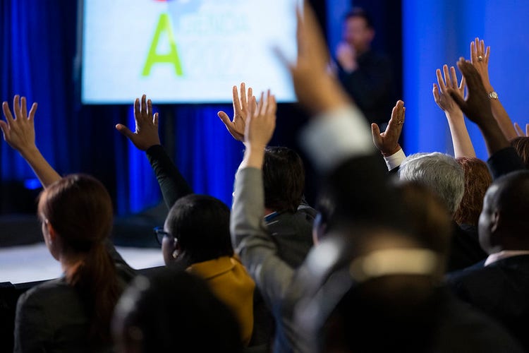 People raising their hand at a conference